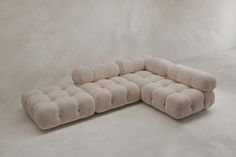 a large beige couch sitting on top of a white floor next to a gray wall