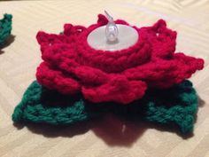 two crocheted flowers sitting on top of a table next to a candle holder