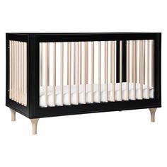 a black crib with white sheets and wood trims on the bottom half, in front of a white background