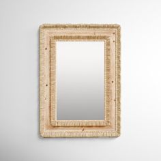 a mirror hanging on the wall next to a white wall with a light brown frame