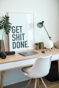 a white desk topped with a laptop computer next to a plant and a phone on top of it