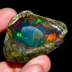 a hand holding an opal stone in it's palm