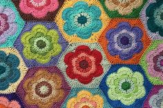 a crocheted blanket with multicolored flowers on it's sides and center