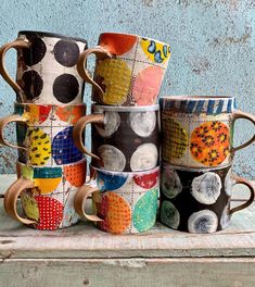 four coffee mugs are stacked on top of each other in different colors and designs