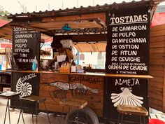 the food cart is decorated with black and white lettering on it's sides, along with two wooden chairs