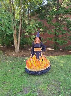 a woman dressed as a witch sitting on top of a fire pit in the grass