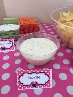 a table topped with bowls filled with dips and veggies next to other snacks