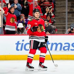 a hockey player is holding his arms up in celebration with the crowd behind him as he skates on the ice