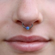 a woman's nose with a single blue opal piercing on top of it