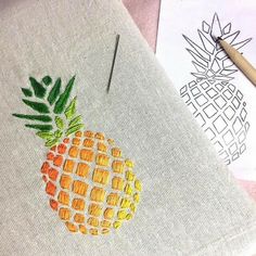 an embroidered pineapple on a piece of linen next to a needle and some other items