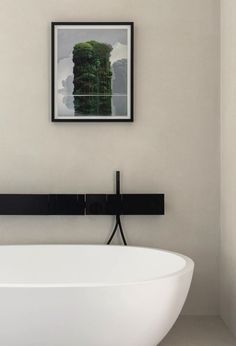 a large white bath tub sitting next to a painting on the wall in a bathroom