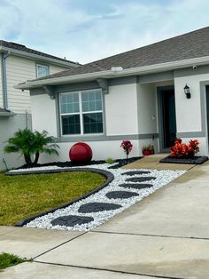 a white house with black and red decorations on the front yard, grass and flowers