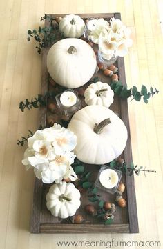 some white pumpkins and flowers on a wooden tray