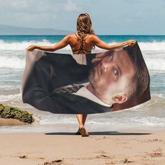 a woman is walking on the beach with a large towel in front of her back