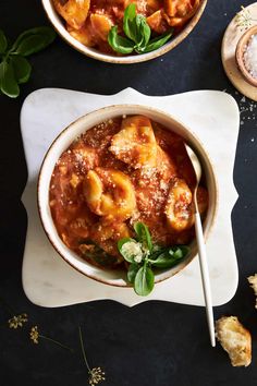 two bowls filled with pasta and sauce on top of a table