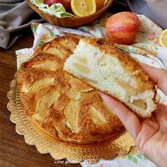 a person holding a piece of bread on top of a plate next to some fruit