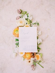 the wedding stationery is laid out on the floor with flowers and greenery around it