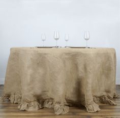 three wine glasses sitting on top of a table with a cloth draped over the table