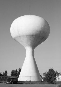 a large white water tower sitting in the middle of a parking lot