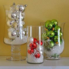 three glass vases filled with ornaments and snow