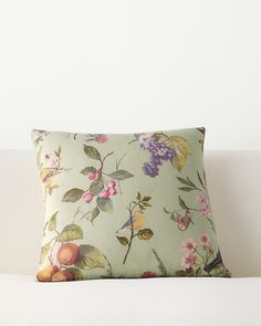 a white couch with a green floral pillow sitting on it's back end,