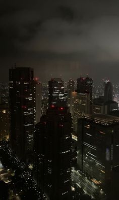 the city skyline is lit up at night with red lights and skyscrapers in the background