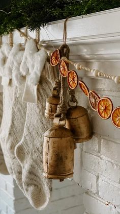 an old fashioned bell hanging from a mantel with orange slices and cinnamons on it