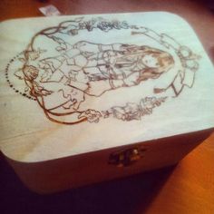 a wooden box sitting on top of a table next to a pen and ink drawing