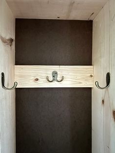 a wooden shelf with two hooks on it