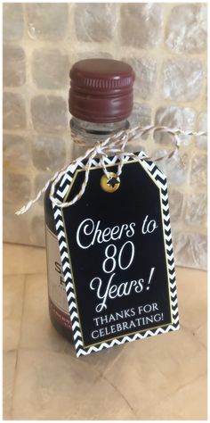 a bottle of wine with a sign on it that says cheers to 80 years thanks for celebrating