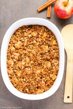 an apple and cinnamon baked oatmeal in a white bowl next to two wooden spoons