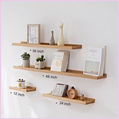 two wooden shelves with books and vases on them next to each other in front of a white wall