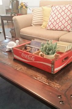 an old coca - cola box is sitting on a coffee table in front of a couch