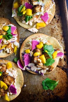 four tacos with meat, vegetables and sauce on a baking sheet ready to be eaten