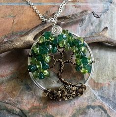 We handmade this unique & gorgeous wire wrapped Tree of Life pendant necklace. The pendant is made with Peridot & dark green Jade gemstones using .925 sterling silver wires for the outer ring, vintage bronze wires for the tree trunk & branches. The pendant measures between 1.60 to 1.70 inch in diameter. It comes with your choice of chain. Each pendant is handmade, so please allow slight variations from the shape of the branches and placement of the stones as shown. The Tree of Life i Wire Wrapped Pendant Necklaces For May Birthstone, Wire Wrapped Round Pendant Necklace For Crafting, Wire Wrapped Necklaces As May Birthstone Gift, Green Hand Wrapped Adjustable Necklace, Adjustable Hand Wrapped Green Necklace, Adjustable Green Hand-wrapped Necklace, Green Wire Wrapped Pendant Jewelry, Nature-inspired Wire Wrapped Crystal Pendant Necklaces, Green Wire Wrapped Pendant