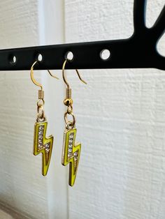 the earrings are hanging from the hook on the coat rack, which is decorated with yellow and white crystals