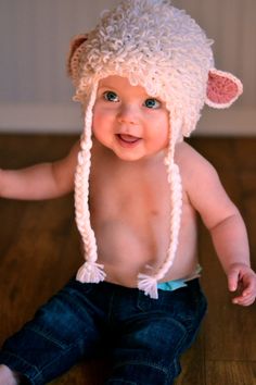 a baby wearing a sheep hat on top of a wooden floor