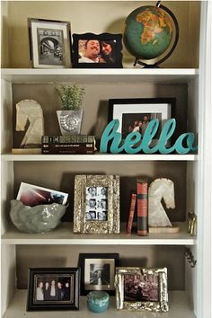 a book shelf with pictures and other items on it, including an hello sign above the bookshelf