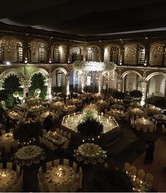 an indoor venue with tables, chairs and chandeliers lit up at night time