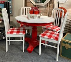 a red and white table with two chairs next to a mirror on the wall above it