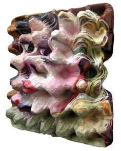 an artistic sculpture made out of clay with different colors and shapes on it's face