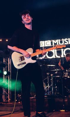 a man standing on top of a stage holding a guitar