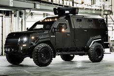 an armored vehicle parked in a warehouse with lights on it's roof and door open