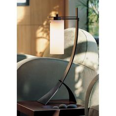 a table lamp sitting on top of a wooden table next to a couch in a living room