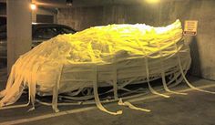 a car covered in plastic wrap sitting on top of a parking lot