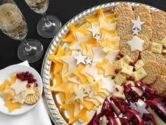 a platter with crackers, cranberry sauce and cheese on it next to two wine glasses