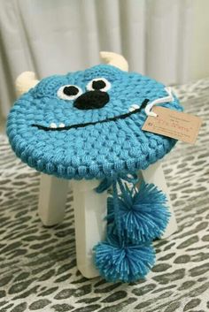 a blue crocheted stool with a monster face on it