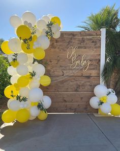 balloons and greenery decorate the entrance to a baby shower