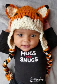 a baby wearing a knitted hat that says hugs and snugs