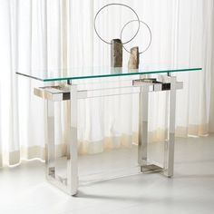 a glass and metal console table in front of a window